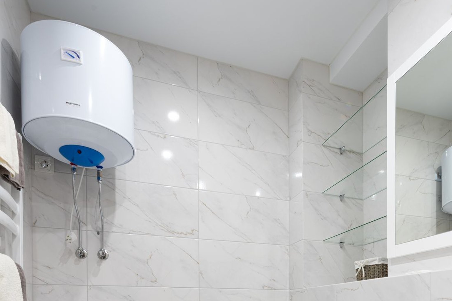 Chauffe-eau électrique mural raccordé par flexibles inox et robinets d'arrêt dans une salle d'eau carrelée